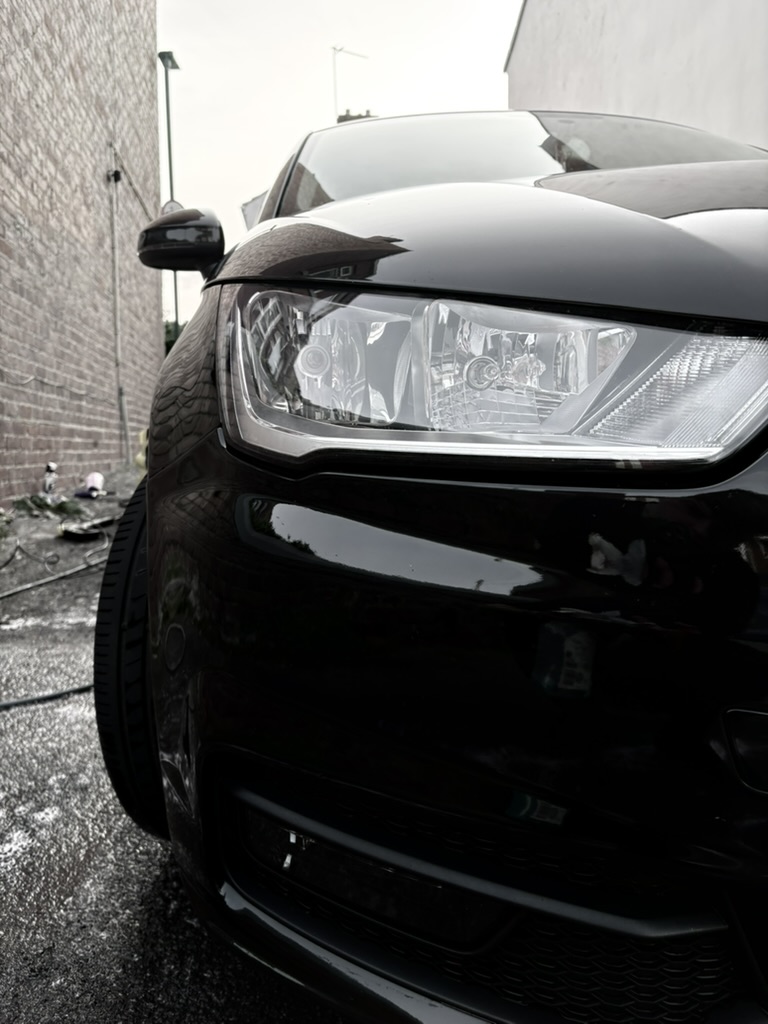 Gleaming black car headlight close-up after detailing