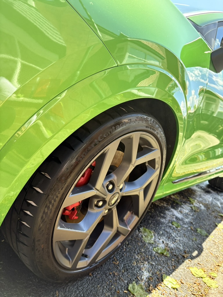 Glossy green car with clean alloy wheel and red brake caliper