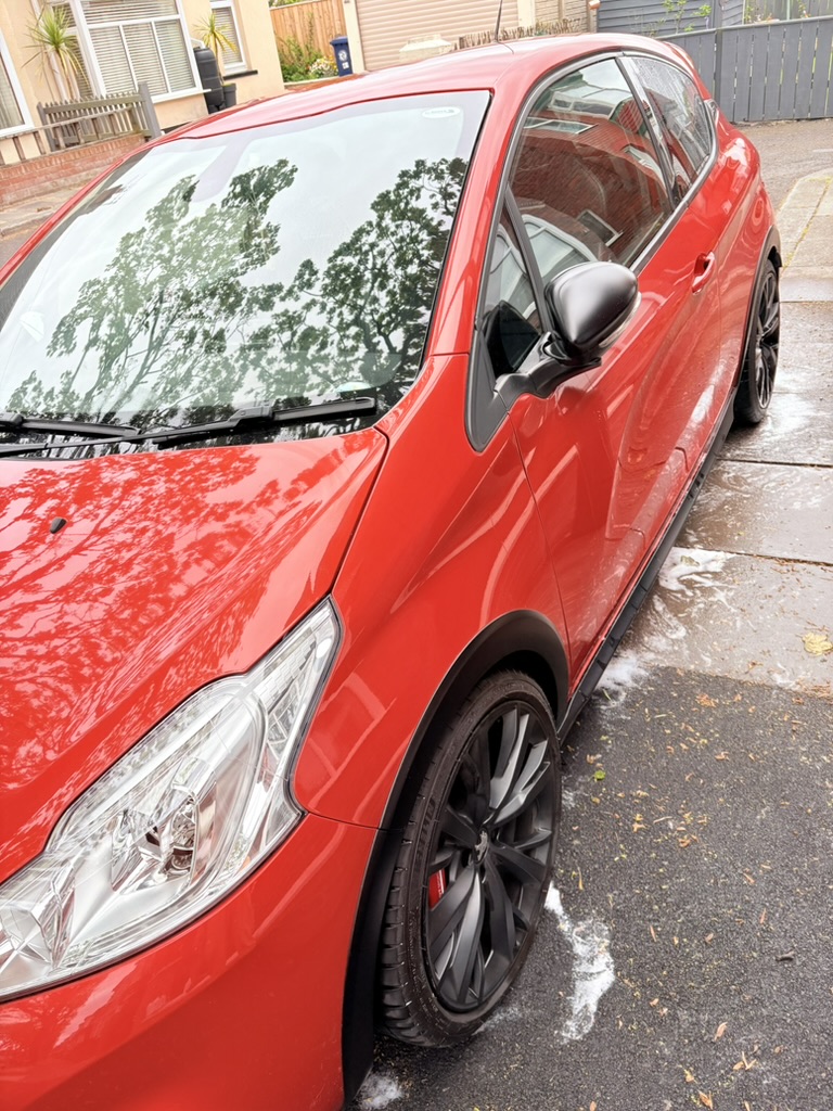 Glossy red hatchback side profile with snow foam